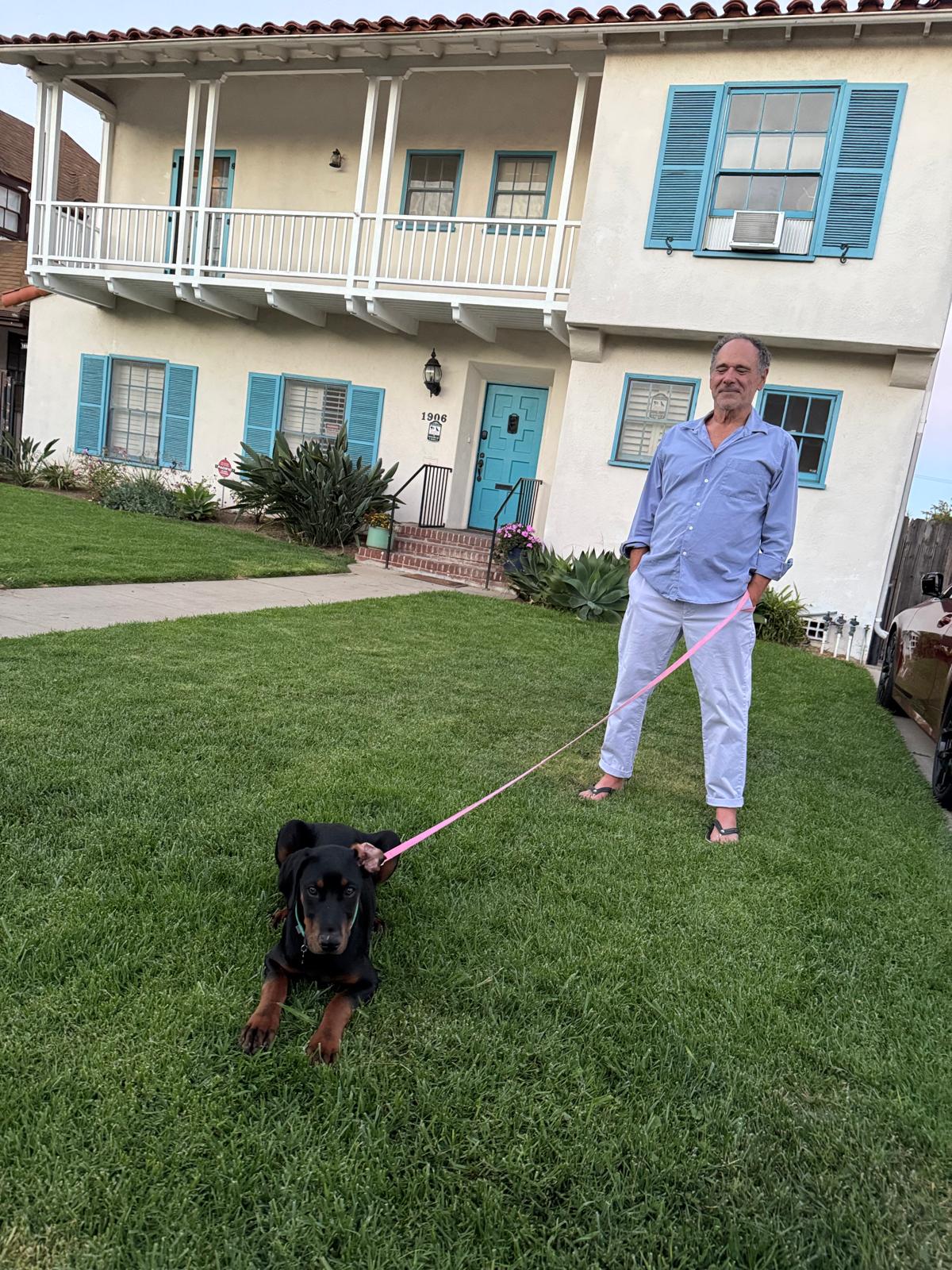 Henry Weil with his Doberman puppy on the lawn of a Spanish-style home